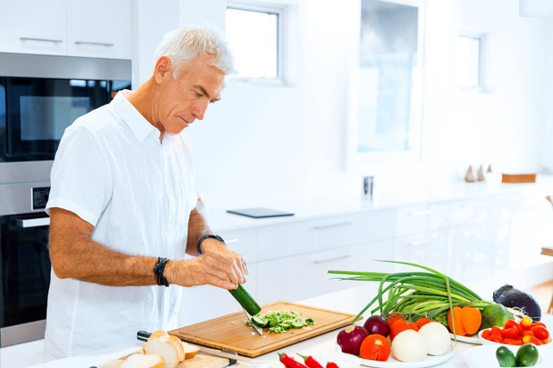 Portrait of a smart senior man standing in kitchen - Φωτογραφία, εικόνα