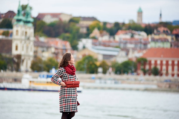 Female tourist is enjoying view of Buda side of Budapest with the Buda Castle, St. Matthias and Fisherman's Bastion. Background blurred. Her hair is blown by the wind - Фото, изображение