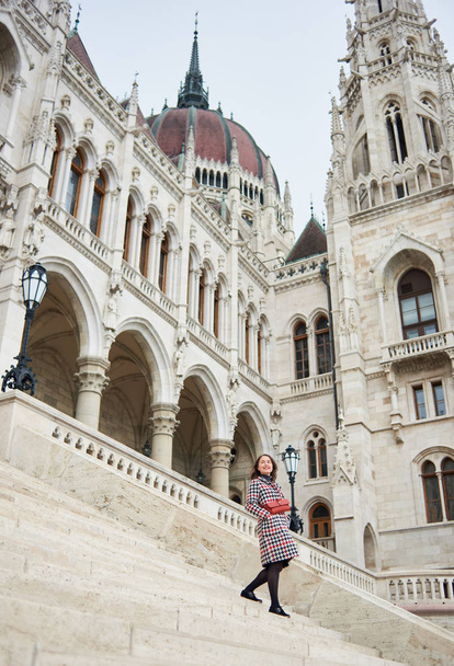 Femme descend les marches de la structure architecturale de la ville de Budapest. Palais du Parlement à Budapest, Hongrie. Photo d'en bas. Automne
 - Photo, image