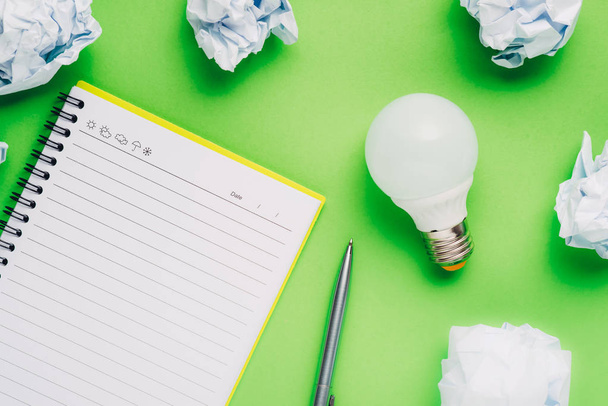 Note book and light bulb on green background. - Foto, Imagem