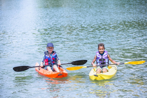 Two boys drifting on kayaks at lake - 写真・画像