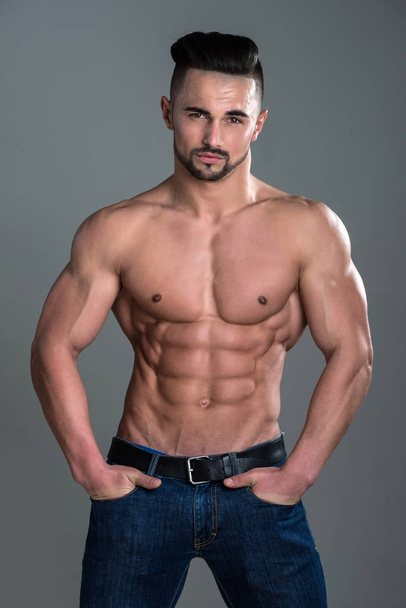 Athletic bodybuilder man on grey background. - Fotografie, Obrázek