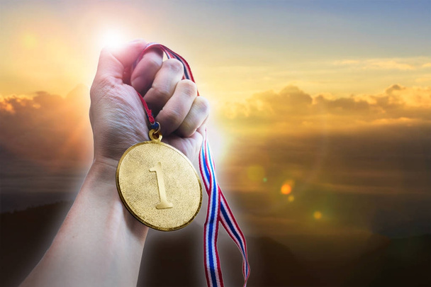 Empresario mano sosteniendo medalla de moneda de oro en la colina
. - Foto, Imagen