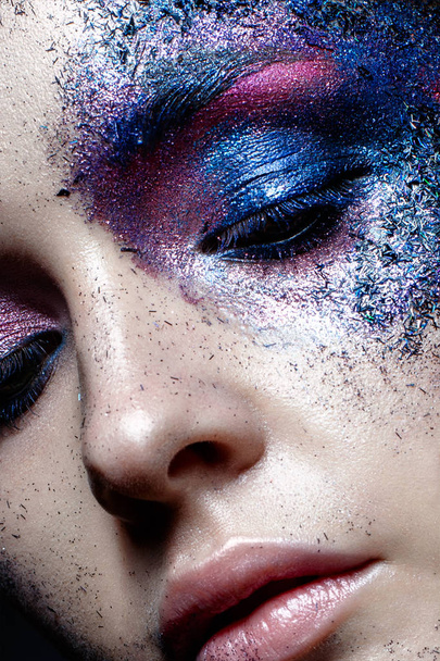 Young girl with creative makeup with texture. Beautiful model with sparkles. Trendy purple smokies. Beauty of face, shining skin. Closeup portrait. Photo is taken in the studio. - Φωτογραφία, εικόνα