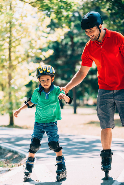 Padre e figlio pattinaggio a rotelle nel parco
  - Foto, immagini