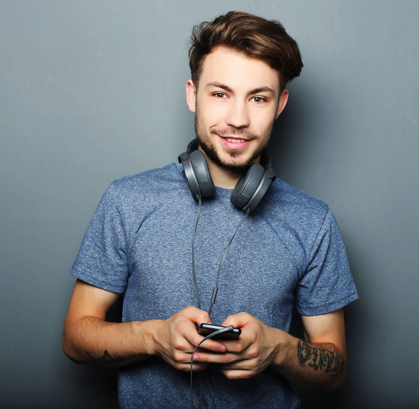 Handsome young man wearing headphones on his neck and smiling wh - 写真・画像