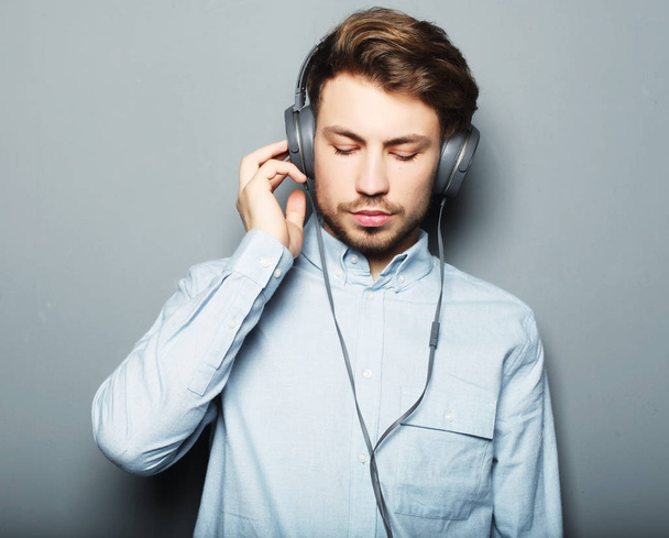 Happy young stylish man  adjusting his headphones ad smiling wh - Foto, imagen