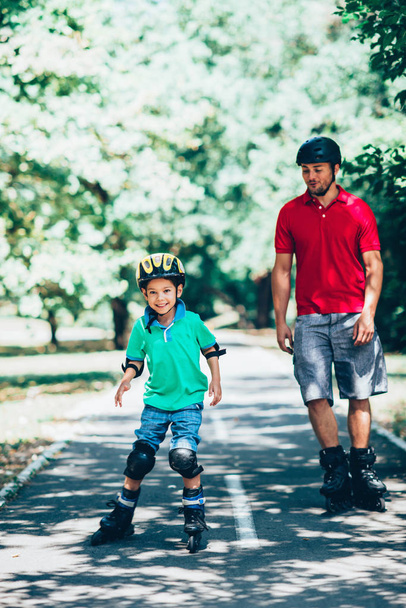 Vater und Sohn beim Rollschuhlaufen im Park  - Foto, Bild