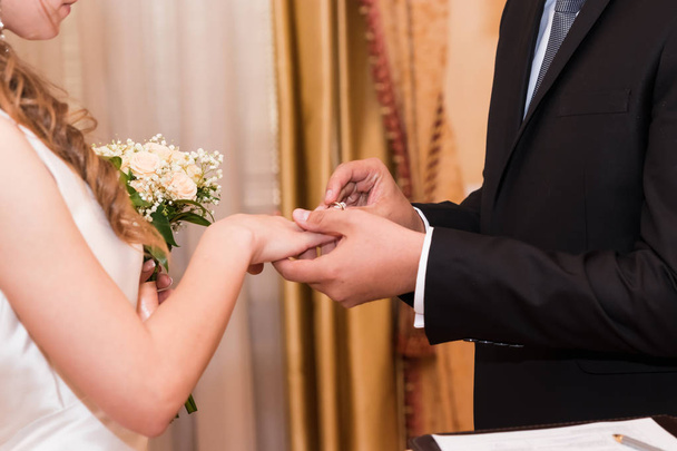 обручальные кольца и руки жениха и невесты. молодожены на церемонии. замужество. мужчина и женщина влюблены. два счастливых человека празднуют вступление в семью. - Фото, изображение