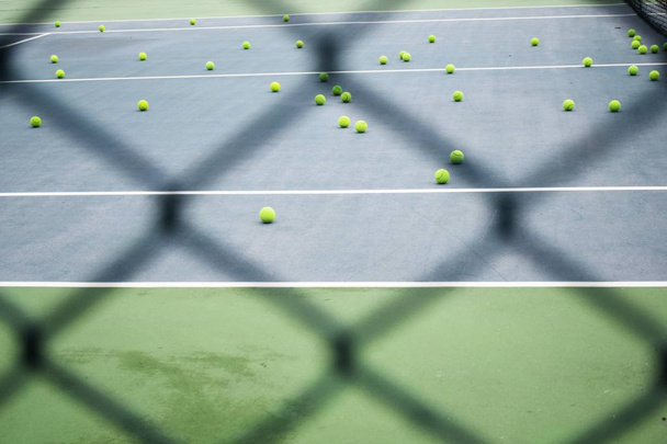 ground court with net and many yellow tennis balls - Foto, Imagen