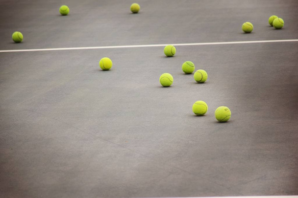 ground court with net and many yellow tennis balls - Fotografie, Obrázek