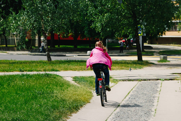 Girl with a guy riding in a park on a bicycle - Foto, immagini
