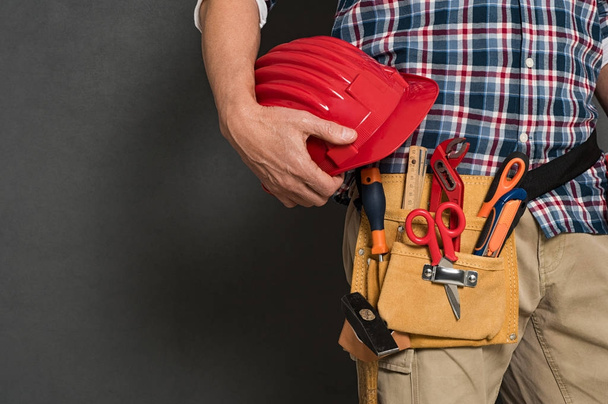 Worker holding hardhat and toolkit - Zdjęcie, obraz