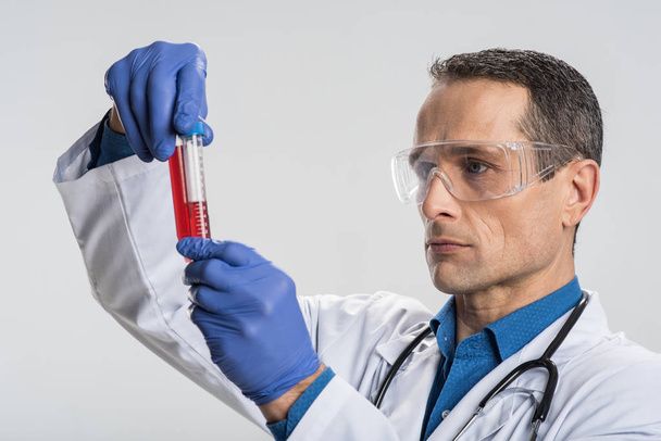 Earnest male laboratorian working with blood sample - Foto, imagen