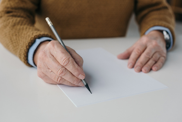 Крупним планом вид на старшого чоловіка, що пише на порожньому папері
 - Фото, зображення