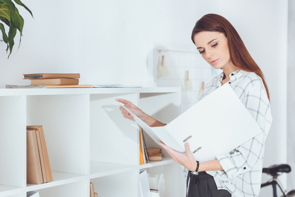 attractive businesswoman looking at documents in folder - Photo, Image