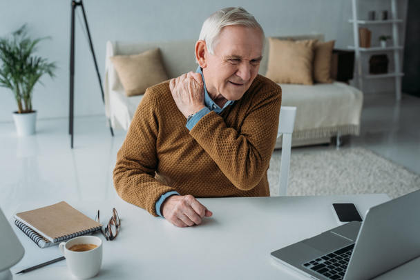Starszy mężczyzna pracujący na laptopie cierpiących na bóle pleców - Zdjęcie, obraz