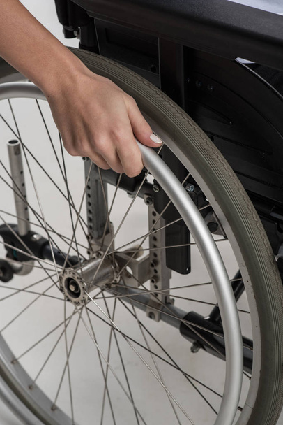 Gros plan de la main féminine placée sur la roue du fauteuil roulant
 - Photo, image