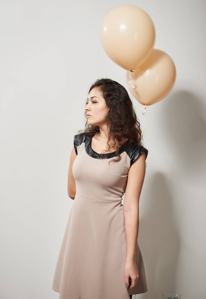 молода жінка або дівчина-підліток в коричневій сукні з повітряними кулями гелію
 - Фото, зображення