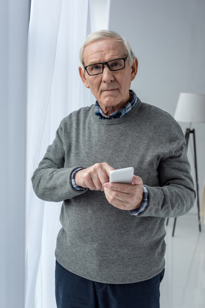 Senior confident man in eyeglasses using smartphone - Photo, Image