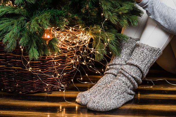 Photo of bottom of the Christmas tree and legs in warm socks. Christmas and New Year concept - Fotoğraf, Görsel