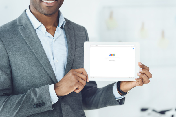 кадроване зображення посміхаючись афроамериканець людиною, показуючи табличка з завантажені google сторінці - Фото, зображення