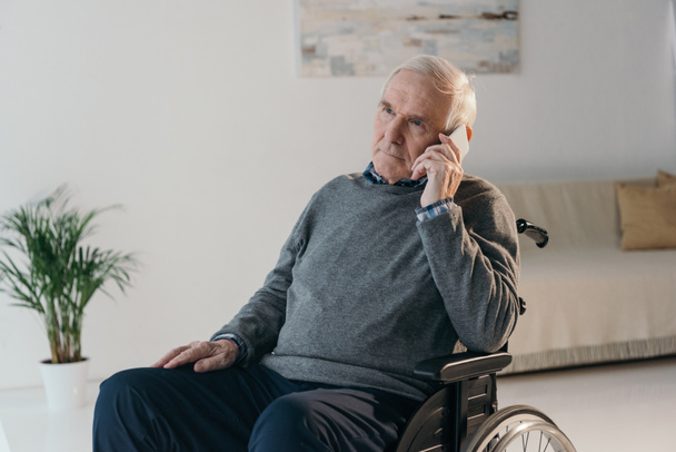 Uomo anziano in sedia a rotelle fare una telefonata in camera vuota
 - Foto, immagini