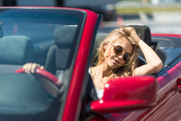Krásná blond dívka v červené kabrioletem. Slunečný den - Fotografie, Obrázek