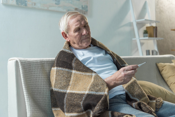 Hombre mayor comprobando la temperatura corporal con termómetro
 - Foto, Imagen