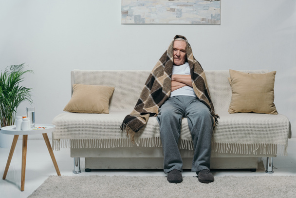 Senior homme réfrigéré couvert de plaid assis sur le canapé
 - Photo, image