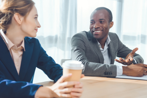 african man smiling to woman with coffe in hands  at office space - Foto, Bild