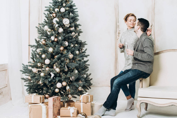 Mutlu çiftimiz Noel süslemeleri ile beyaz odada. Noel ve yeni yıl kavramı - Fotoğraf, Görsel