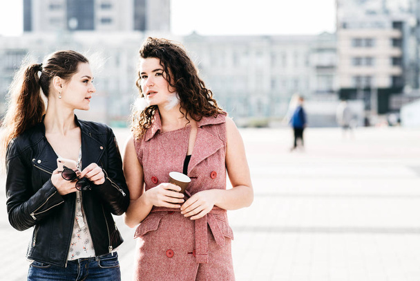 Duas namoradas atraentes se comunicam na praça da cidade
 - Foto, Imagem
