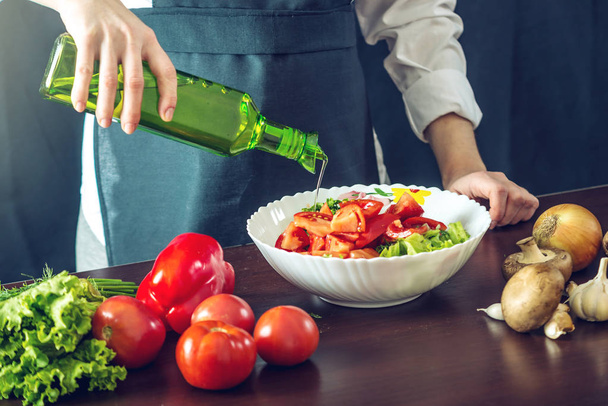 ブラック エプロンのシェフ野菜サラダになります。調理のための環境に優しい製品のコンセプト - 写真・画像