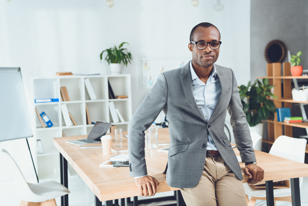 african man leaning on table and looking at camera at office space  - Photo, Image
