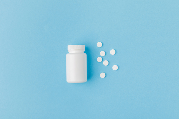 container and scattered pills isolated on blue background   - Photo, Image