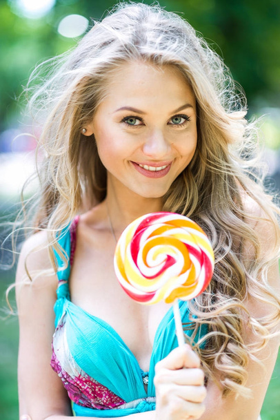 Attractive blond girl with a lollipop in the park in summer - Foto, Bild