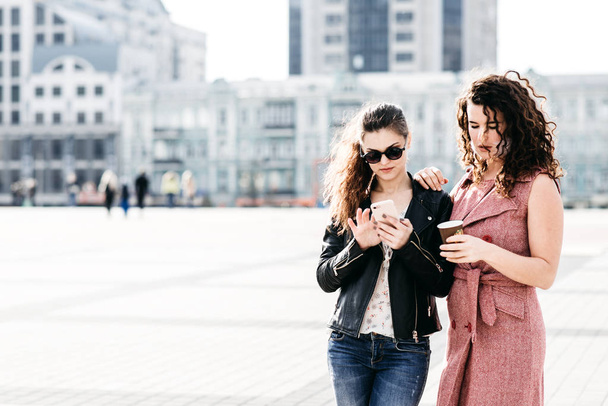 Дві привабливі подружки спілкуються на площі міста
 - Фото, зображення