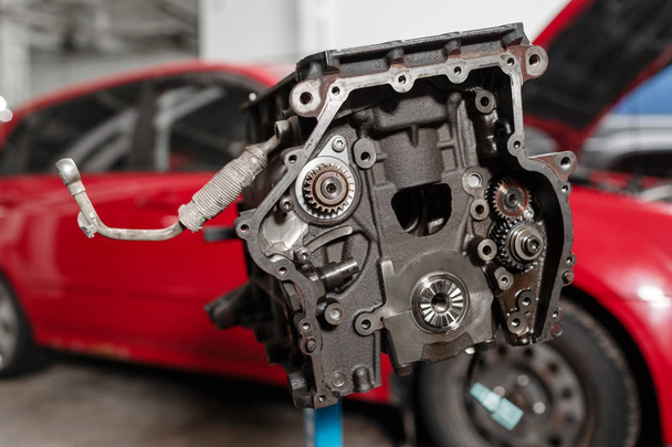 Seçici odak. Motor bloğu onarım stand Piston ve marjbiyel otomotiv teknolojisi ile. Arka plan üzerinde kırmızı araba bulanık. Bir araba tamir dükkanı iç. - Fotoğraf, Görsel