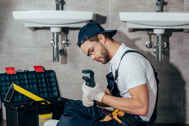 young professional plumber fixing sink in bathroom - Photo, Image