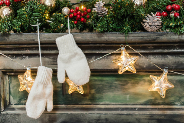 Christmas decorations on the fireplace, white gloves. Christmas and New Year concept - Photo, image