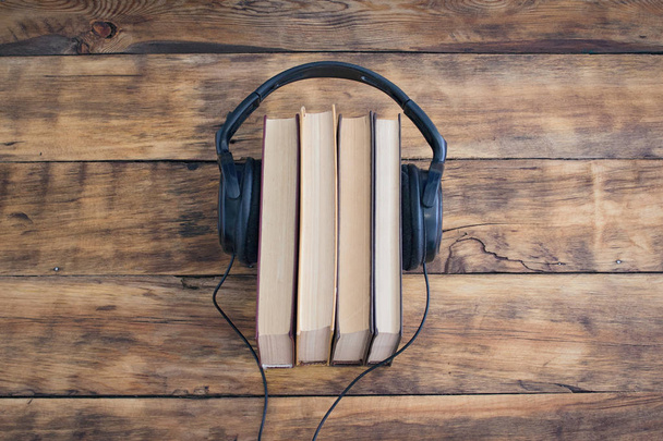 Ακουστικά για το σωρό των βιβλίων πάνω στο ξύλινο τραπέζι. Ηχογραφημένα βιβλία. - Φωτογραφία, εικόνα