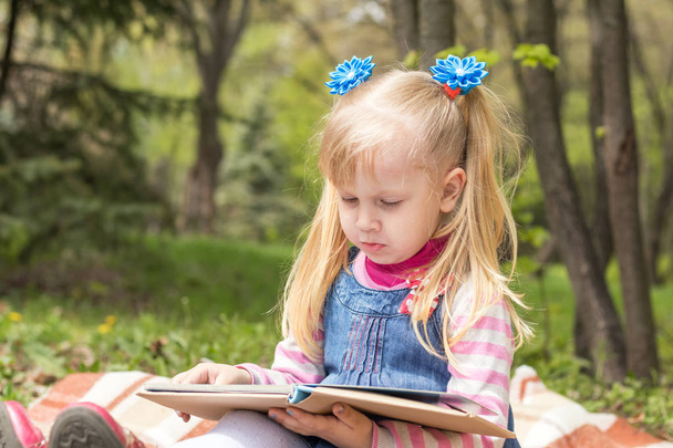 Милая маленькая блондинка с двумя хвостиками, расслабляющая с книгой
  - Фото, изображение