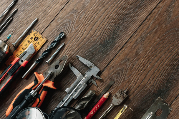 A construction tool on a brown wooden background. View from above. Picture background, screensaver. The concept of construction, repair, construction, production, design. Copy space. - 写真・画像