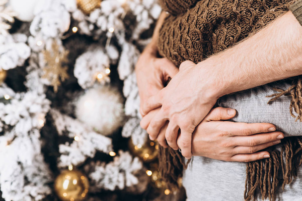 Hands close-up. Young happy couple near a Christmas tree. Christmas and New Year concept - Valokuva, kuva
