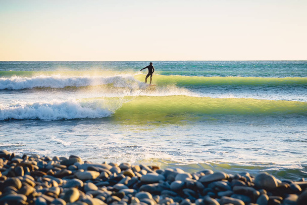 Surfař jízda na dokonalé oceánu vlnu při západu slunce. Zima surfování v plavkách   - Fotografie, Obrázek