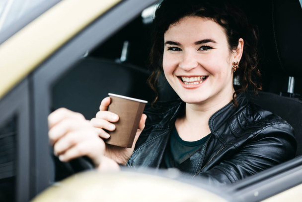 Woman in car indoor keeps wheel turning around smiling - Photo, Image