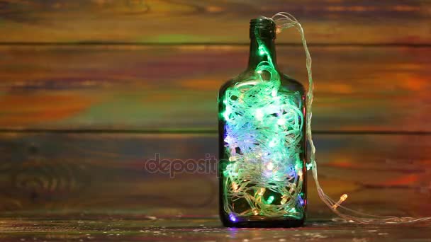 Decorations for the New Year. Garland with flashing lights inside the bottle. Creative solutions. Christmas decorations on wooden background. Free space - Footage, Video