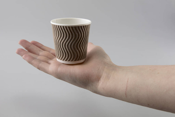 La tazza ondulata per bevande calde è tenuta da una mano femminile
 - Foto, immagini