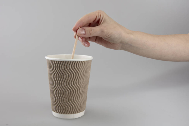 Гофрована чашка для гарячих напоїв тримає жіноча рука
 - Фото, зображення